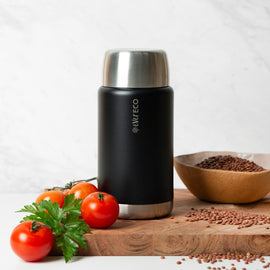 Ever Eco Onyx 800ml insulated food jar thermos with silver top on a wooden cutting board with tomatoes and seeds.